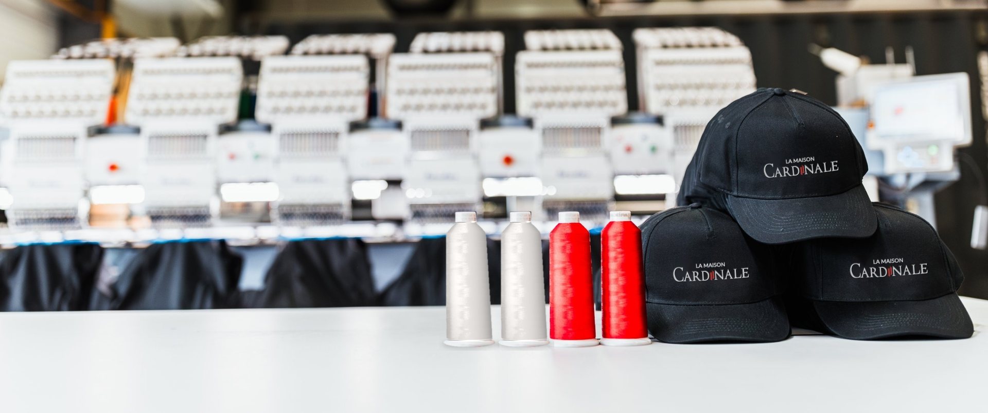 Casquettes brodées au logo de La Maison Cardinale devant les brodeuses de l’atelier Quodao